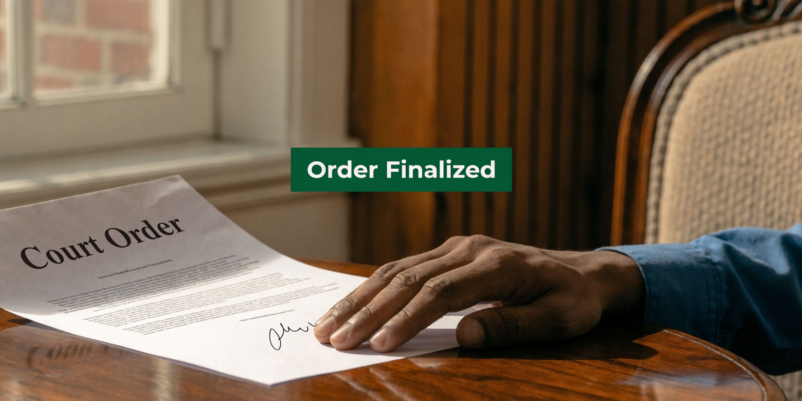 A close-up view of a person signing a formal court order document at a wooden desk.