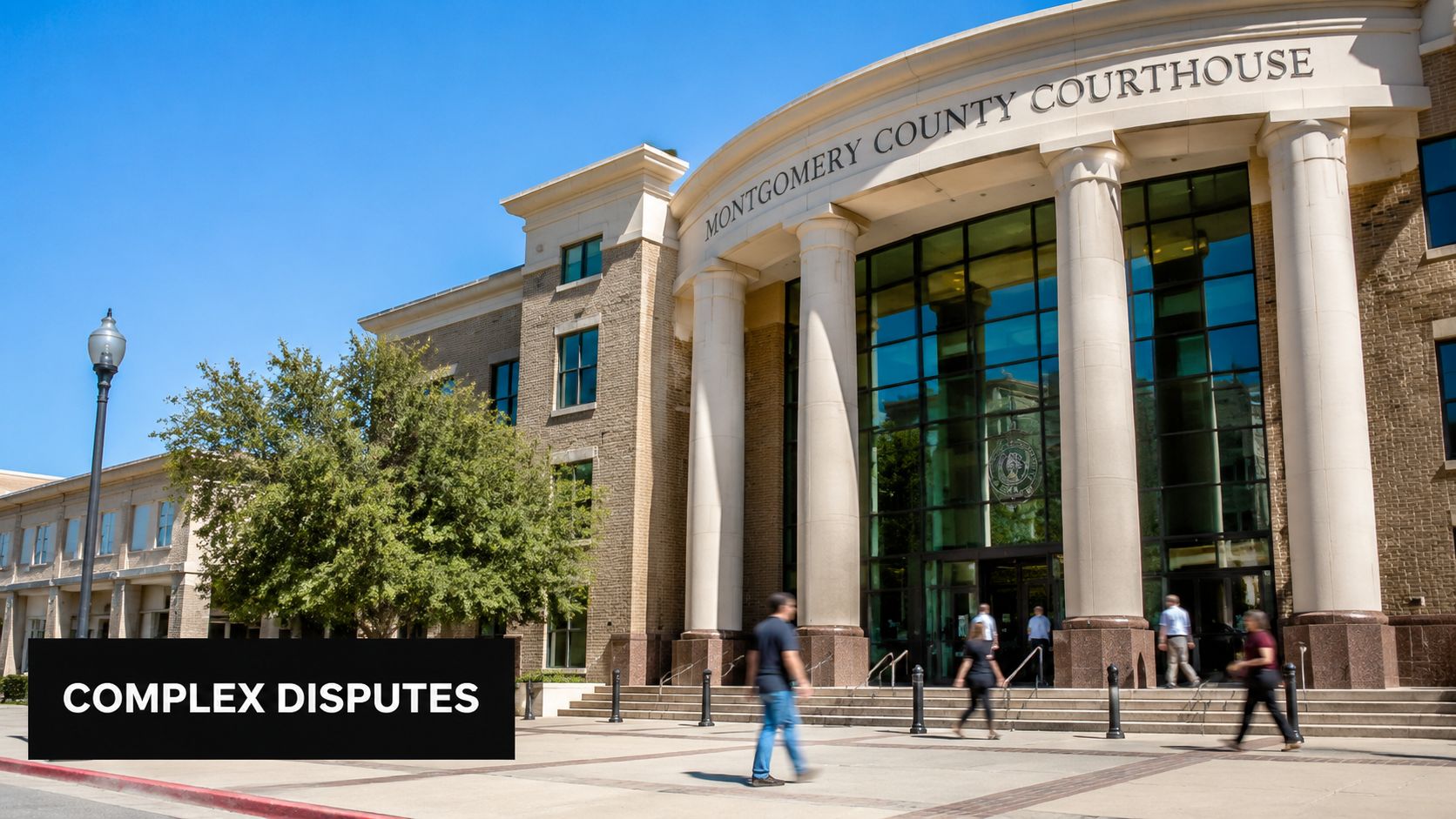 A modern Montgomery County Courthouse building entrance with people walking on the plaza on a sunny day.